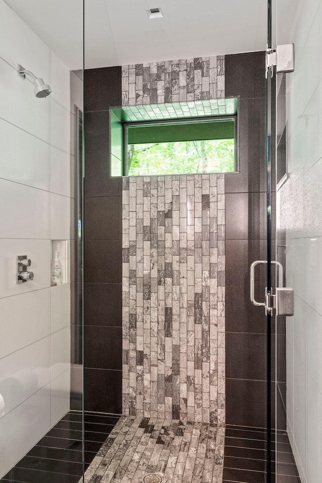 bathroom with an enclosed shower and tile walls