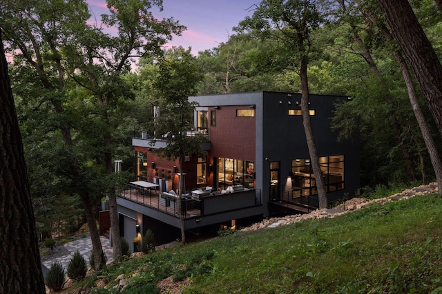 back house at dusk with a wooden deck