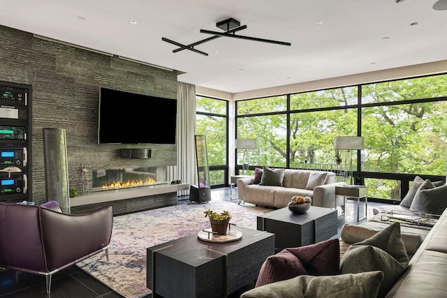 living room with a fireplace, dark tile patterned flooring, ceiling fan, and floor to ceiling windows