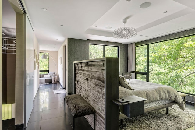 tiled bedroom featuring a tray ceiling and an inviting chandelier