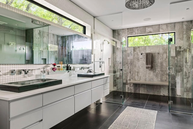 bathroom with tile patterned flooring, vanity, a shower with door, and tasteful backsplash