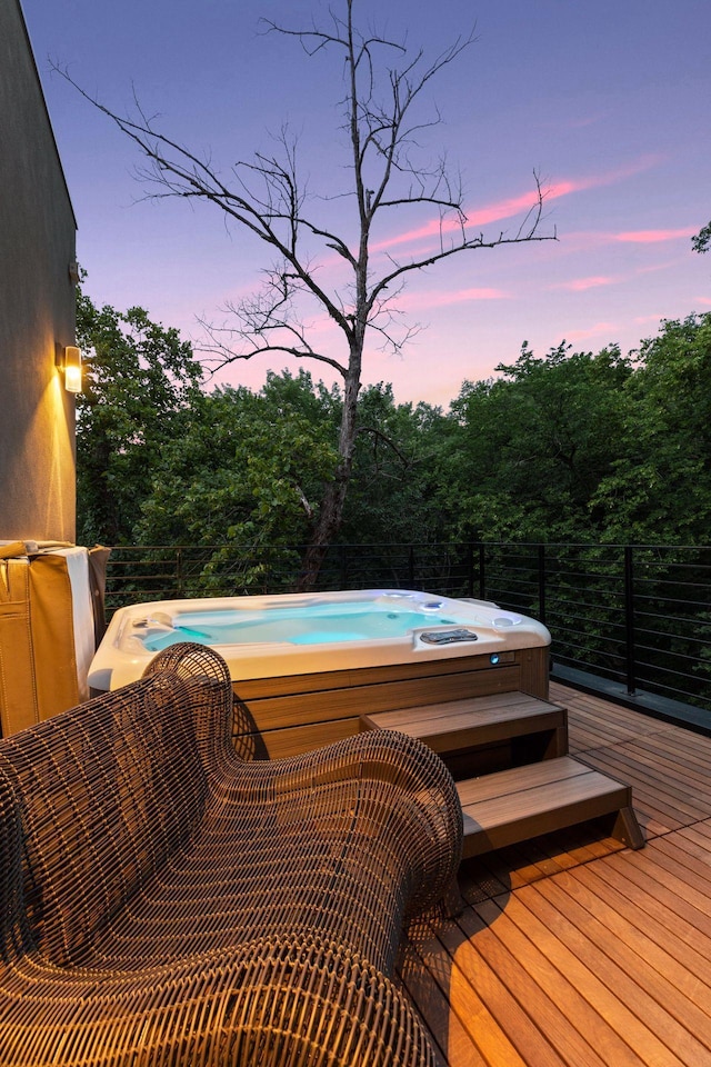 deck at dusk featuring a hot tub