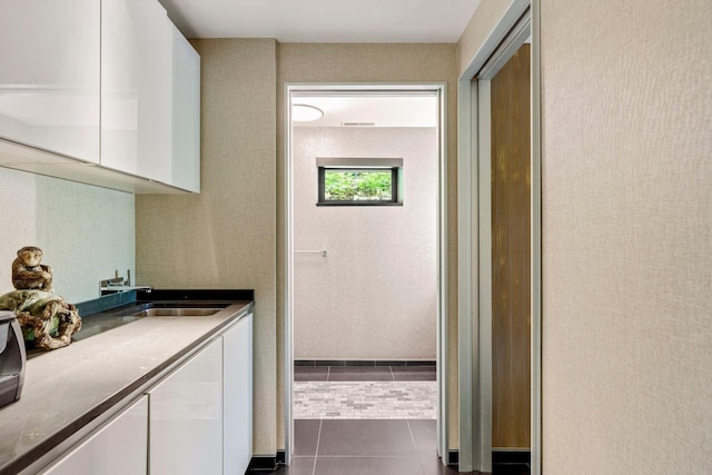 kitchen with white cabinets, dark tile patterned flooring, and sink