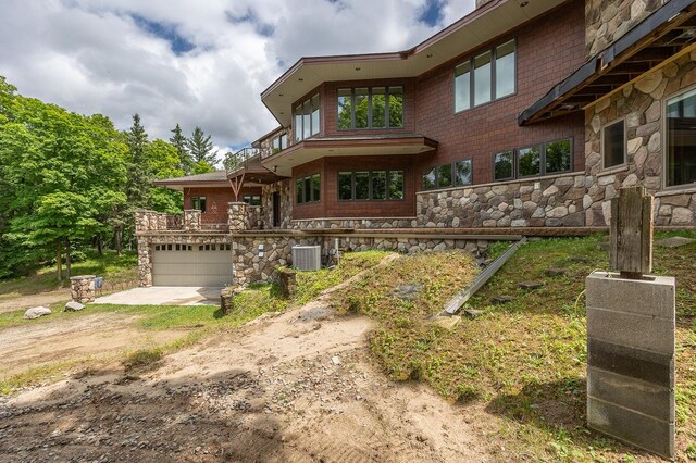 view of front of home with a garage, central AC, and a balcony