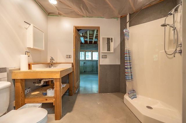 bathroom with a shower, a workshop area, concrete flooring, and toilet