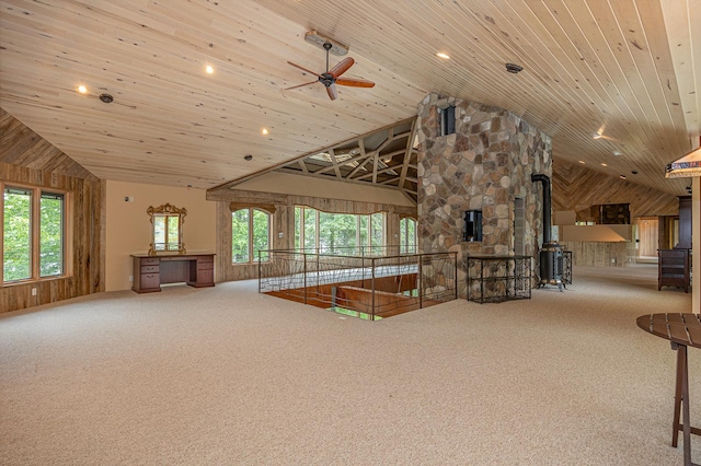 unfurnished living room featuring plenty of natural light, a wood stove, carpet, and wooden ceiling