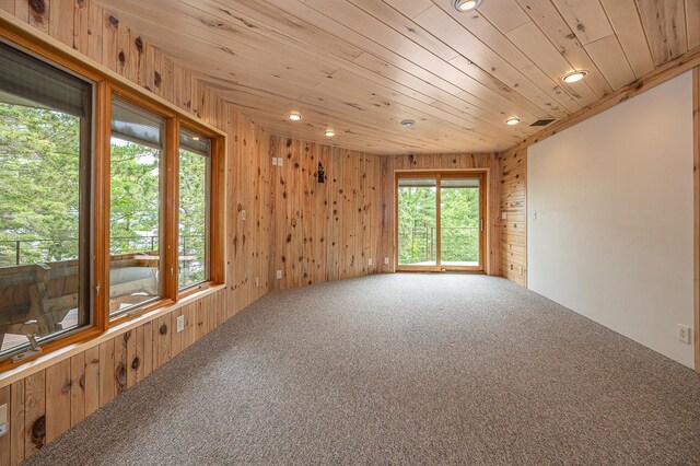 empty room with carpet, wooden walls, and wooden ceiling