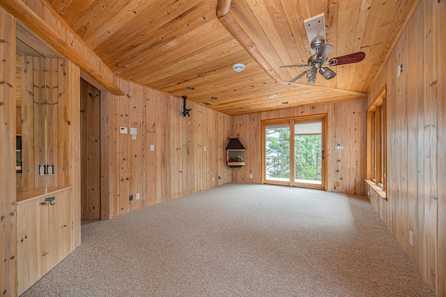 carpeted spare room featuring ceiling fan, wooden walls, and wooden ceiling