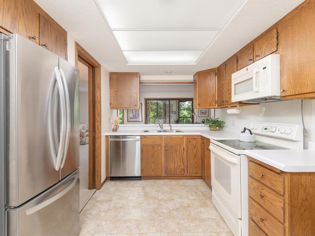 kitchen with a sink, stainless steel appliances, brown cabinetry, and light countertops