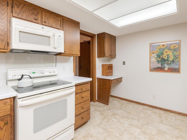 kitchen with brown cabinetry, white appliances, light countertops, and baseboards