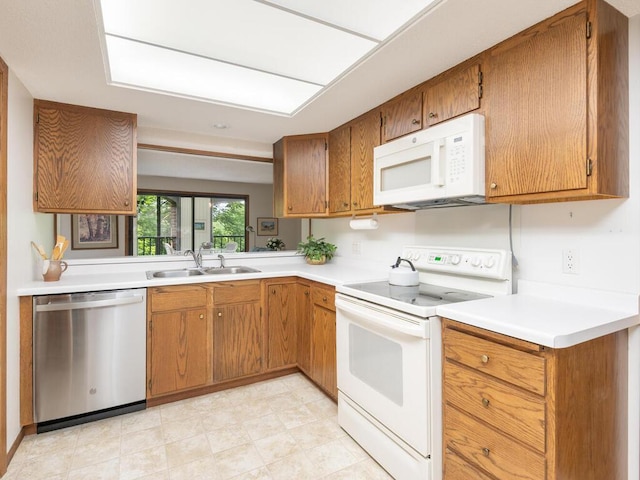 kitchen with white appliances, brown cabinetry, light countertops, and a sink