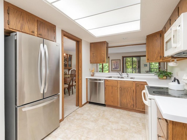 kitchen featuring brown cabinetry, appliances with stainless steel finishes, light countertops, and a sink