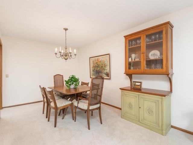 dining area featuring light carpet, baseboards, and an inviting chandelier