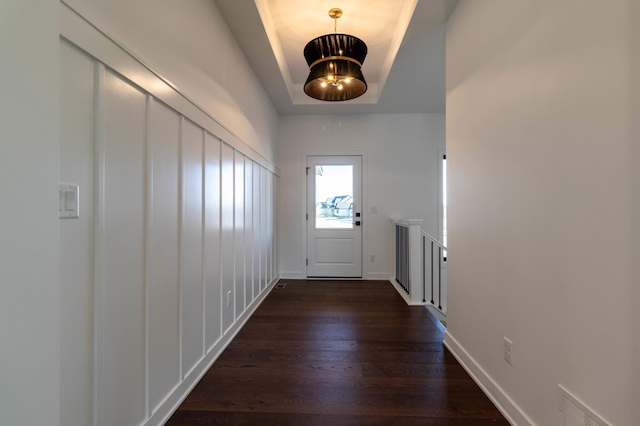 entryway with an inviting chandelier, dark hardwood / wood-style flooring, and a tray ceiling