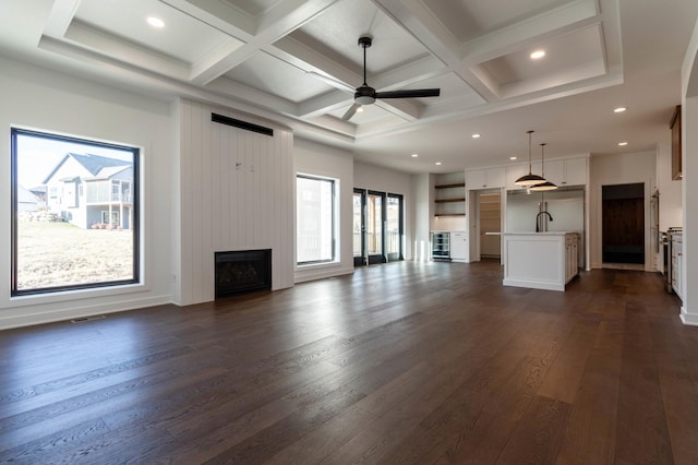 unfurnished living room with a large fireplace, dark wood-type flooring, and coffered ceiling