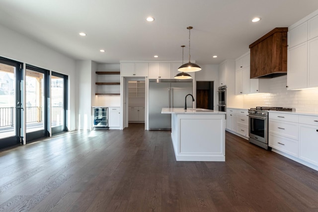 kitchen featuring sink, premium appliances, dark hardwood / wood-style flooring, an island with sink, and decorative light fixtures