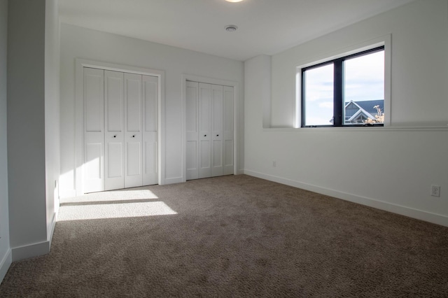 unfurnished bedroom featuring carpet and multiple closets