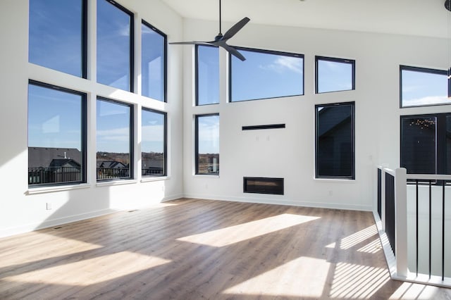 living room with light hardwood / wood-style flooring, high vaulted ceiling, plenty of natural light, and ceiling fan