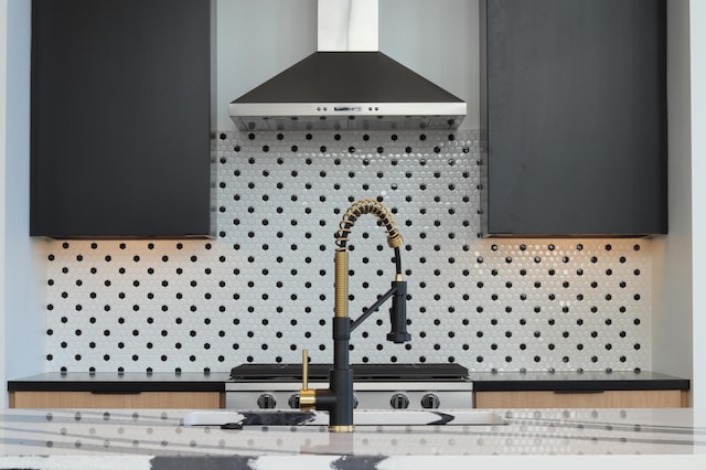 details featuring wall chimney exhaust hood, sink, and decorative backsplash