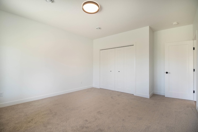 unfurnished bedroom featuring a closet and light colored carpet