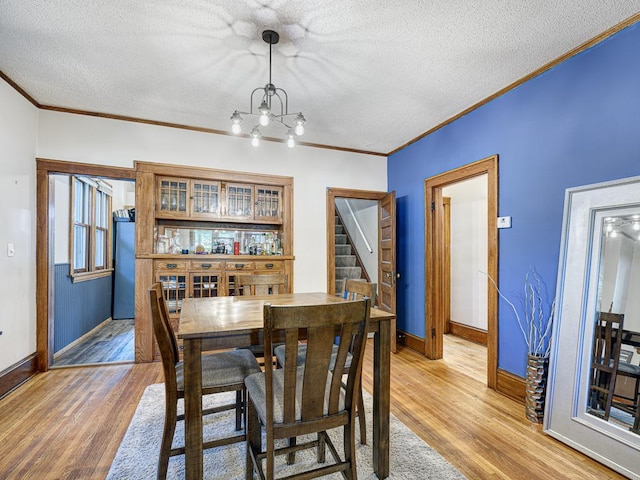 dining room with ornamental molding, hardwood / wood-style floors, and a textured ceiling