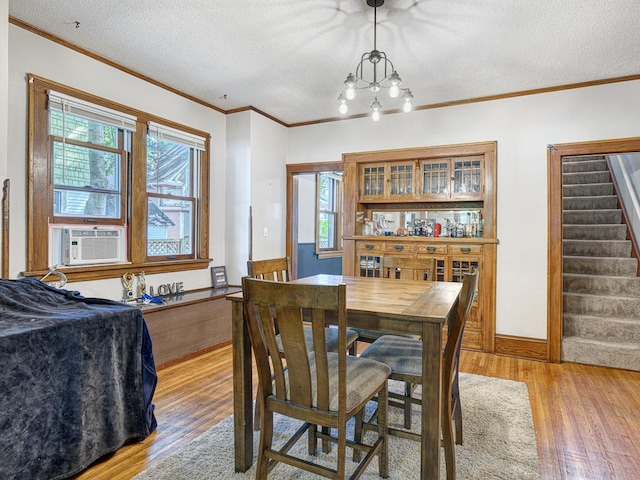 dining space featuring cooling unit, a wealth of natural light, crown molding, and light wood-type flooring