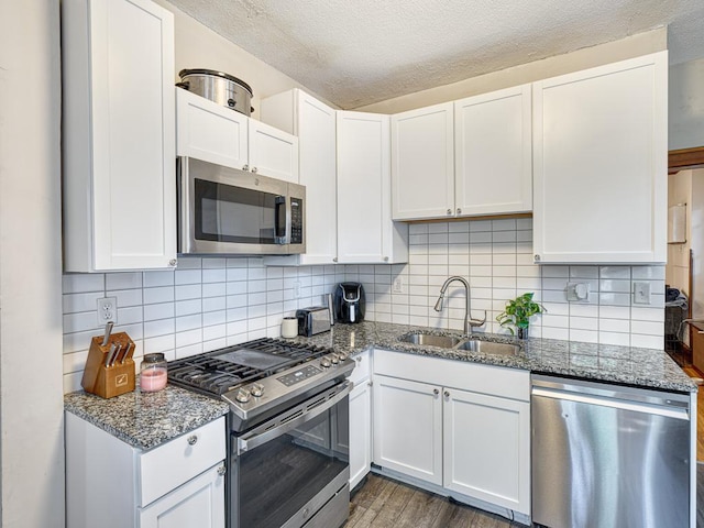 kitchen featuring white cabinetry, sink, dark stone countertops, and appliances with stainless steel finishes