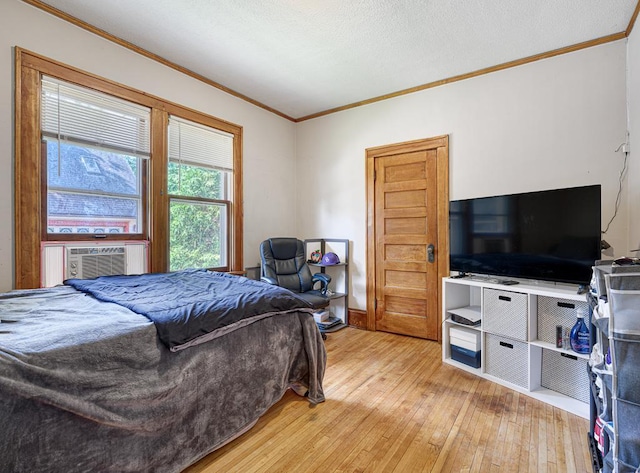 bedroom with cooling unit, crown molding, and light hardwood / wood-style flooring