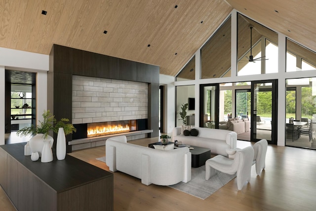 living room with a brick fireplace, wood ceiling, ceiling fan, high vaulted ceiling, and light hardwood / wood-style floors