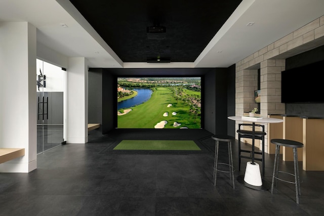 game room featuring a tray ceiling and golf simulator