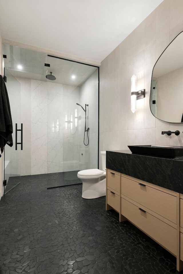 bathroom featuring vanity, toilet, tile walls, and walk in shower