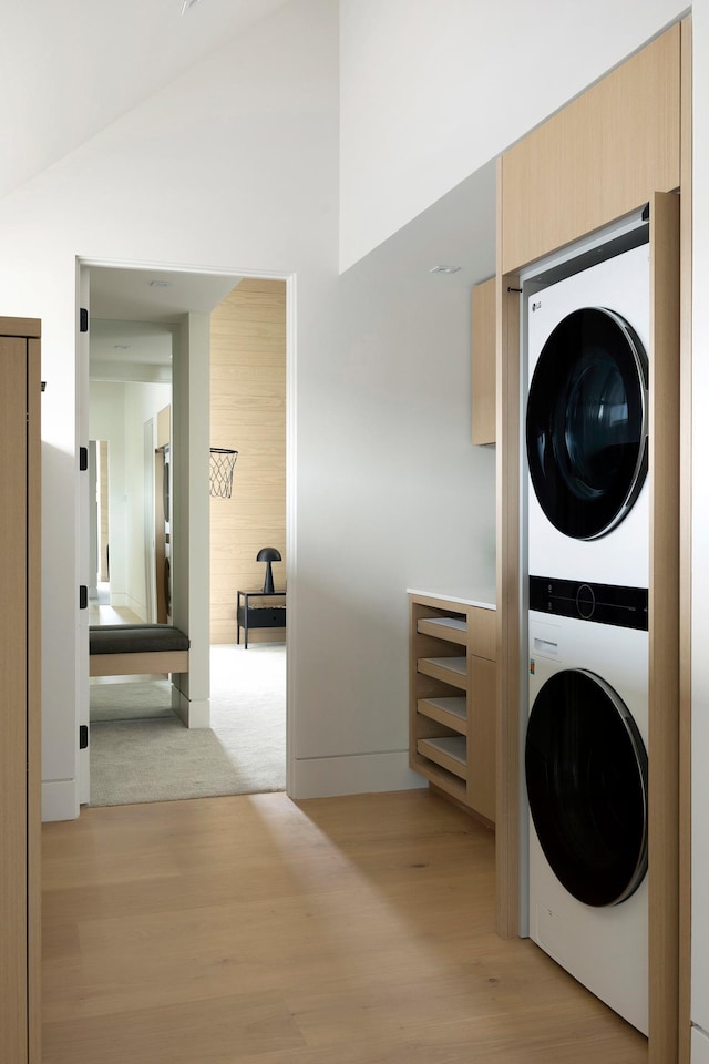 laundry room featuring light wood-type flooring and stacked washer and dryer