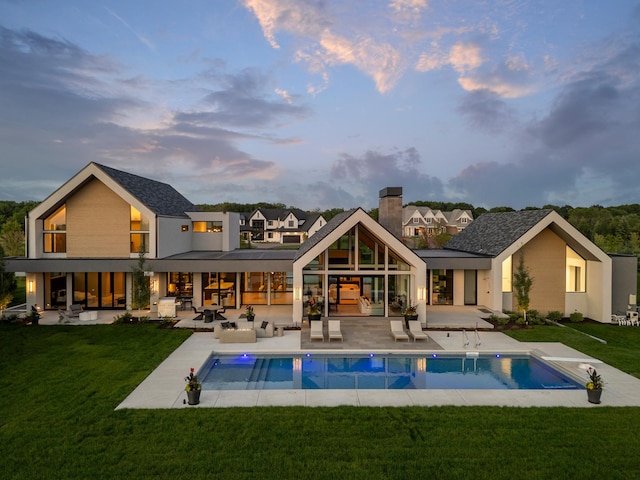 back house at dusk featuring a lawn, an outdoor living space, and a patio area