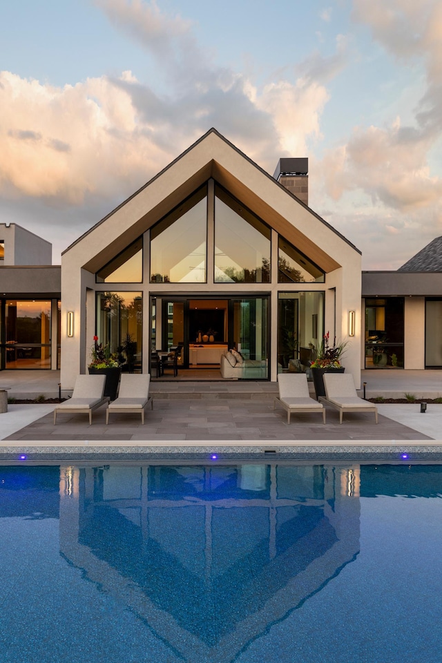 pool at dusk with a patio area