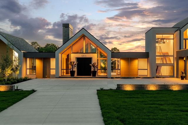 back house at dusk with a lawn