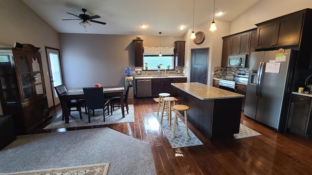 kitchen with a kitchen island, ceiling fan, dark hardwood / wood-style floors, appliances with stainless steel finishes, and decorative backsplash