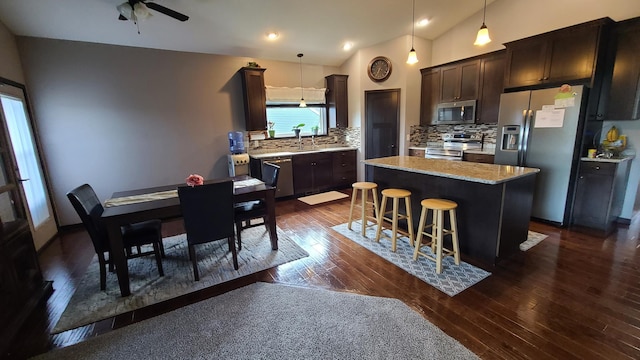 kitchen featuring tasteful backsplash, stainless steel appliances, dark hardwood / wood-style flooring, a center island, and vaulted ceiling