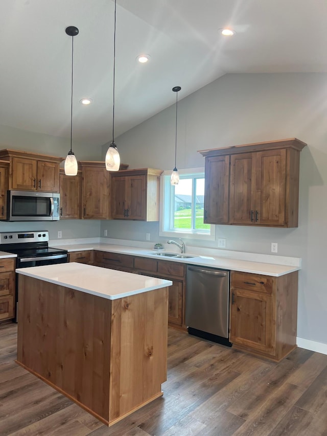 kitchen featuring sink, appliances with stainless steel finishes, hanging light fixtures, a kitchen island, and dark hardwood / wood-style flooring