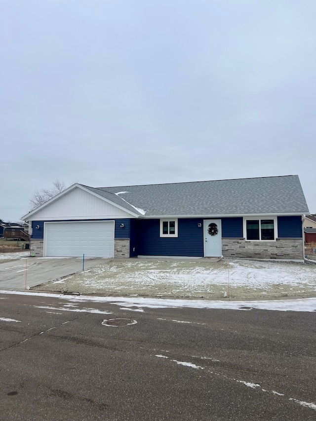 view of front facade with concrete driveway, stone siding, roof with shingles, and an attached garage