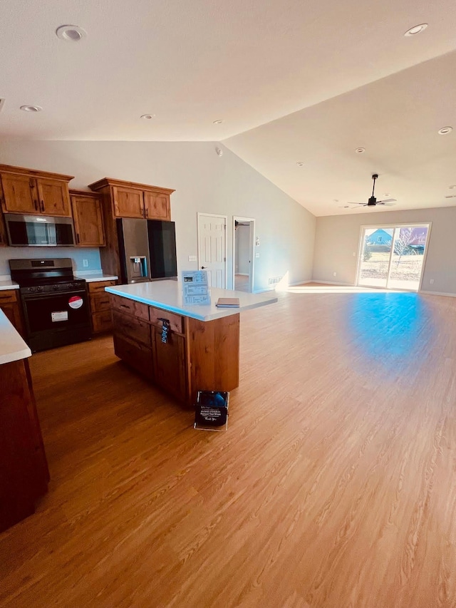 kitchen with open floor plan, light countertops, appliances with stainless steel finishes, a center island, and brown cabinetry