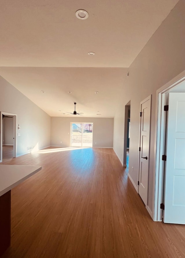 unfurnished living room featuring baseboards, visible vents, a ceiling fan, and wood finished floors