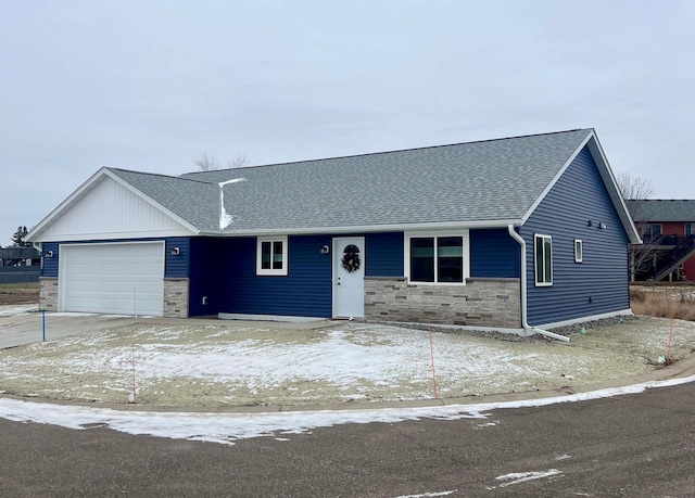 single story home with an attached garage, stone siding, and roof with shingles