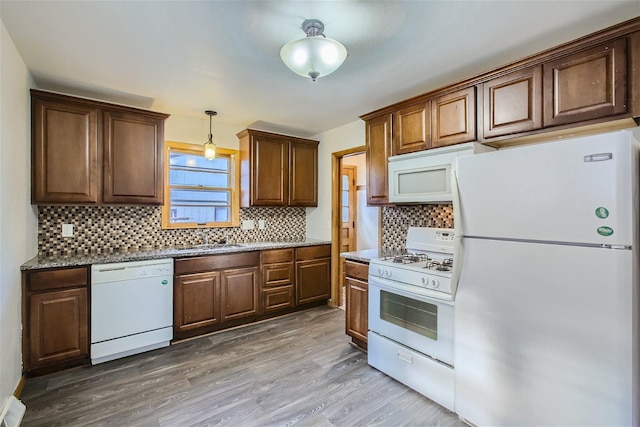 kitchen featuring pendant lighting, sink, hardwood / wood-style flooring, tasteful backsplash, and white appliances