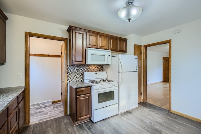 kitchen featuring hardwood / wood-style flooring, backsplash, and white appliances