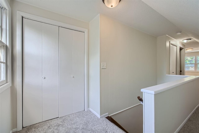 hall with carpet floors and a textured ceiling