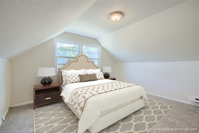 carpeted bedroom with vaulted ceiling and a textured ceiling