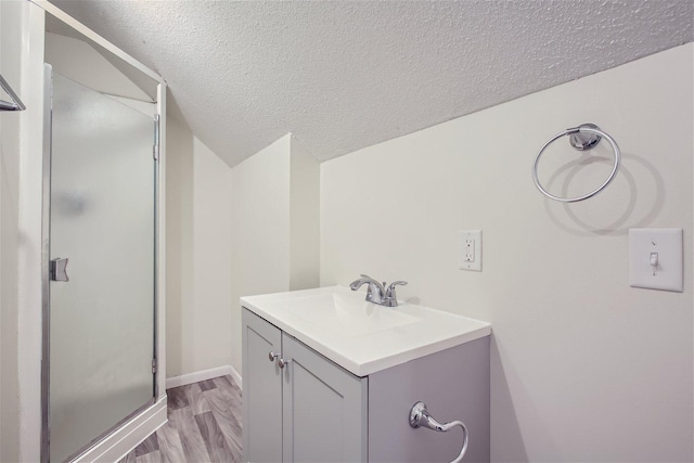 bathroom featuring vanity, hardwood / wood-style flooring, a shower with door, and a textured ceiling