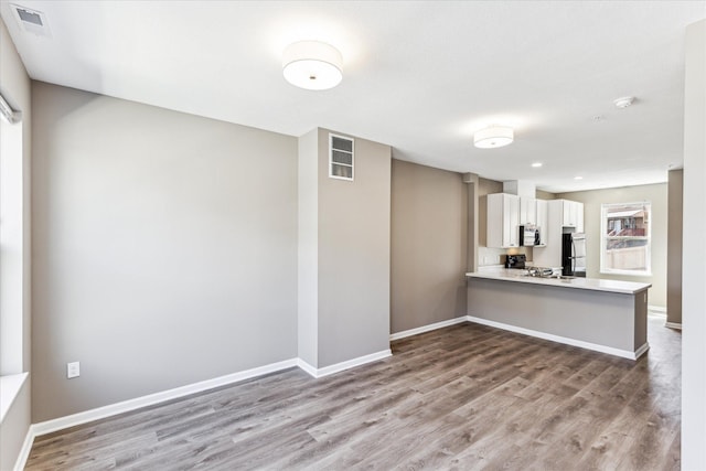 kitchen featuring black refrigerator, white cabinets, hardwood / wood-style flooring, electric range, and kitchen peninsula