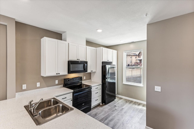 kitchen featuring light stone counters, sink, black appliances, and white cabinets