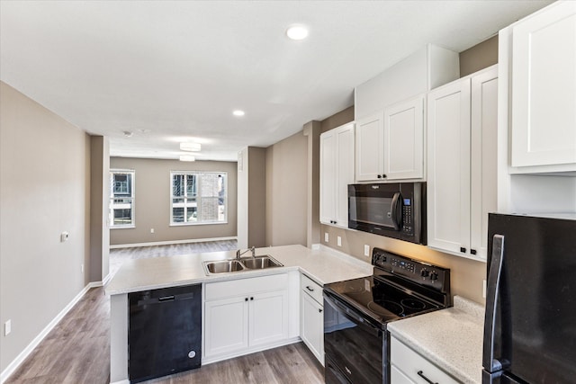 kitchen with white cabinetry, sink, kitchen peninsula, and black appliances